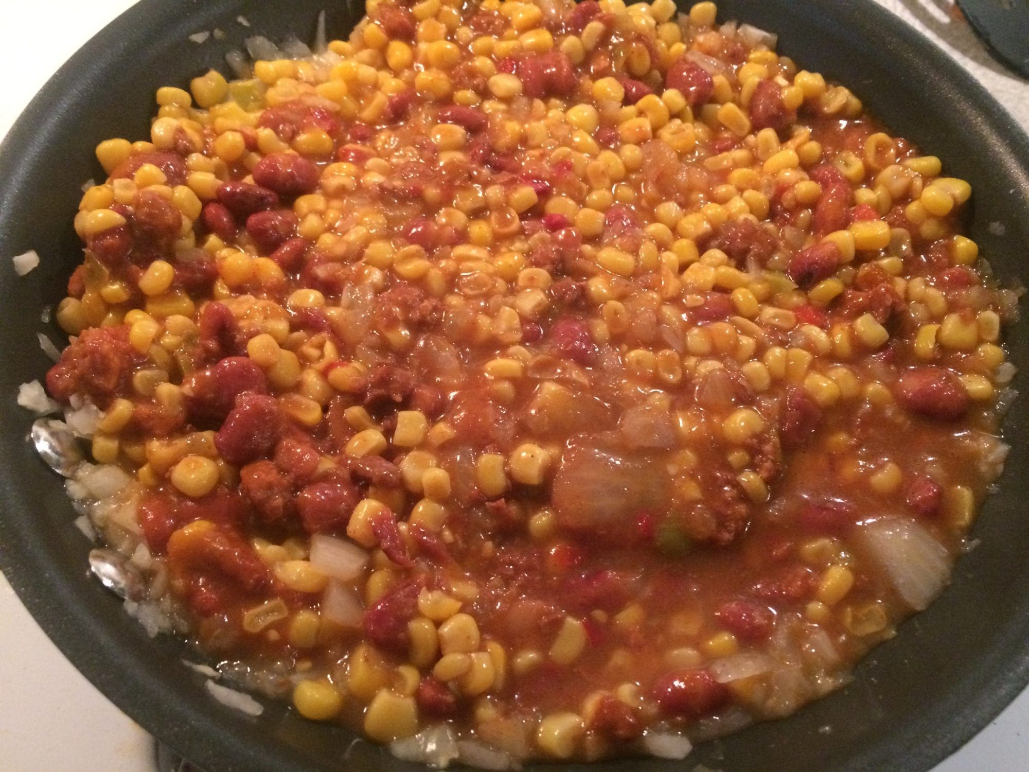 Sprinkled cheese on Mexican canned corn for chili cornbread casserole.