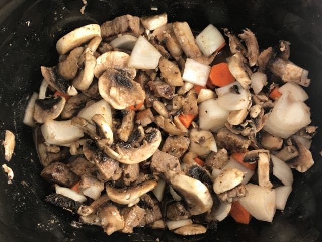Add beef, onion, carrots, and mushrooms to the slow cooker and mix together with the red wine sauce.