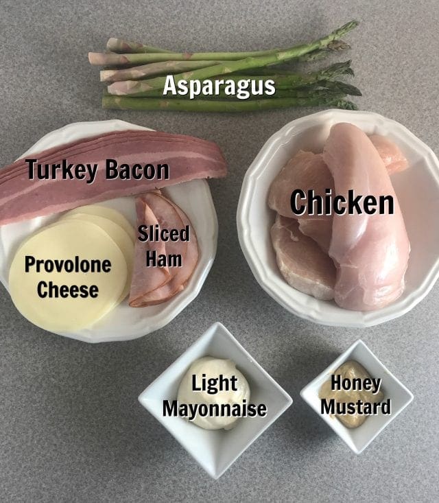 7 Simple ingredients for delicious bacon wrapped chicken roulades - Chicken, asparagus, turkey bacon, sliced ham, provolone cheese, light mayonnaise, and honey mustard.