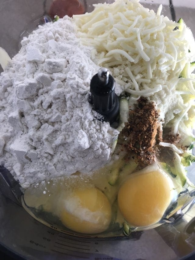 Blend ingredients for a zucchini pizza crust in a food processor.