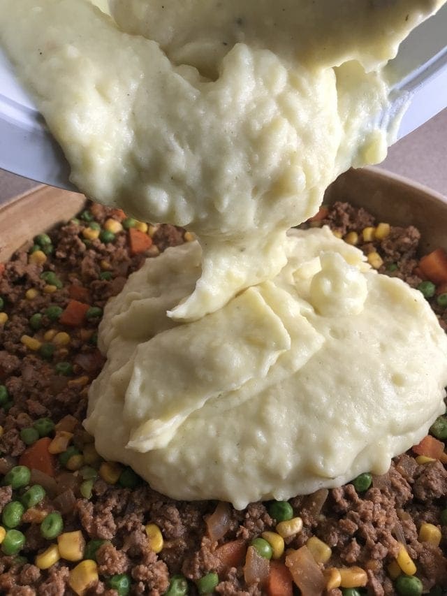 Spoon mashed potatoes over meat and veggie mixture for a shepherd's pie.